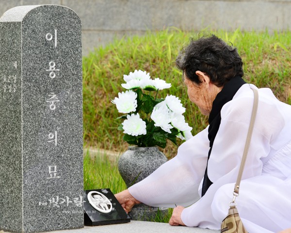 묘비 번호 제1-86번의 고 이용충의 묘비를 스다듬고 아픔을 달래고 있는 어머니, 고 이용충 은 1954년 에 출생하여 1980년 5월 21일 젊은 나리로 이나라의 민주주의를 위해 희생되었다