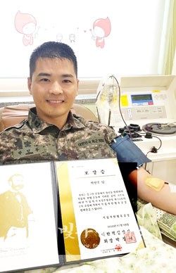 21여년 동안 헌혈을 실천한 박인주 소령이 헌혈의 집에서 대한적십자로부터 받은 헌혈 유공 명예장을 들고 101번 째 헌혈을 하고 있다.